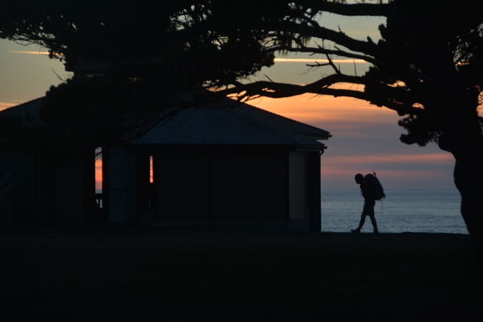 sunset silhouetting a backpacker in the distance
